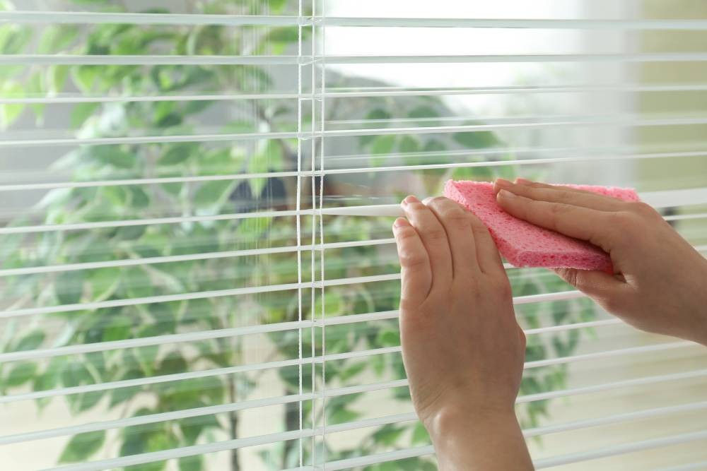 Homeowner cleaning a blind with a sponge near Arvada, Colorado (CO)
